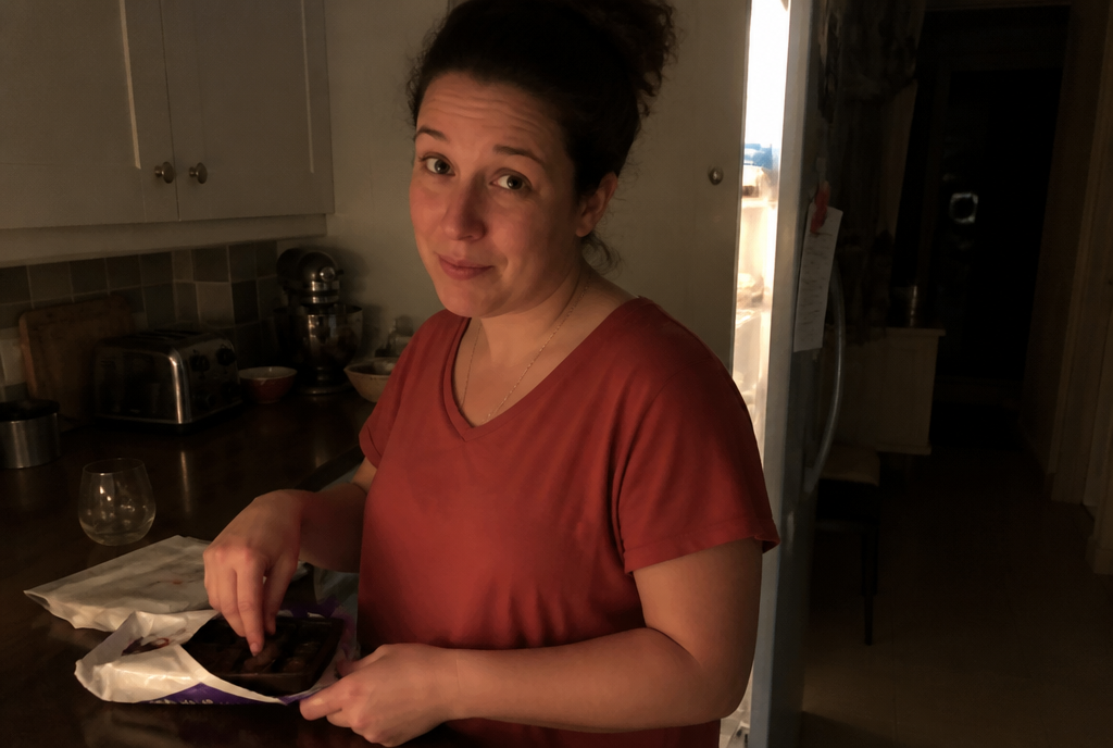 Woman reaching for sugar snack at night