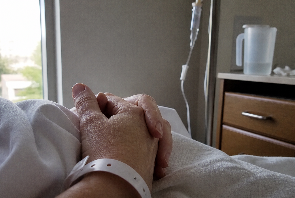 Hands resting on a hospital blanket with an ID wristband