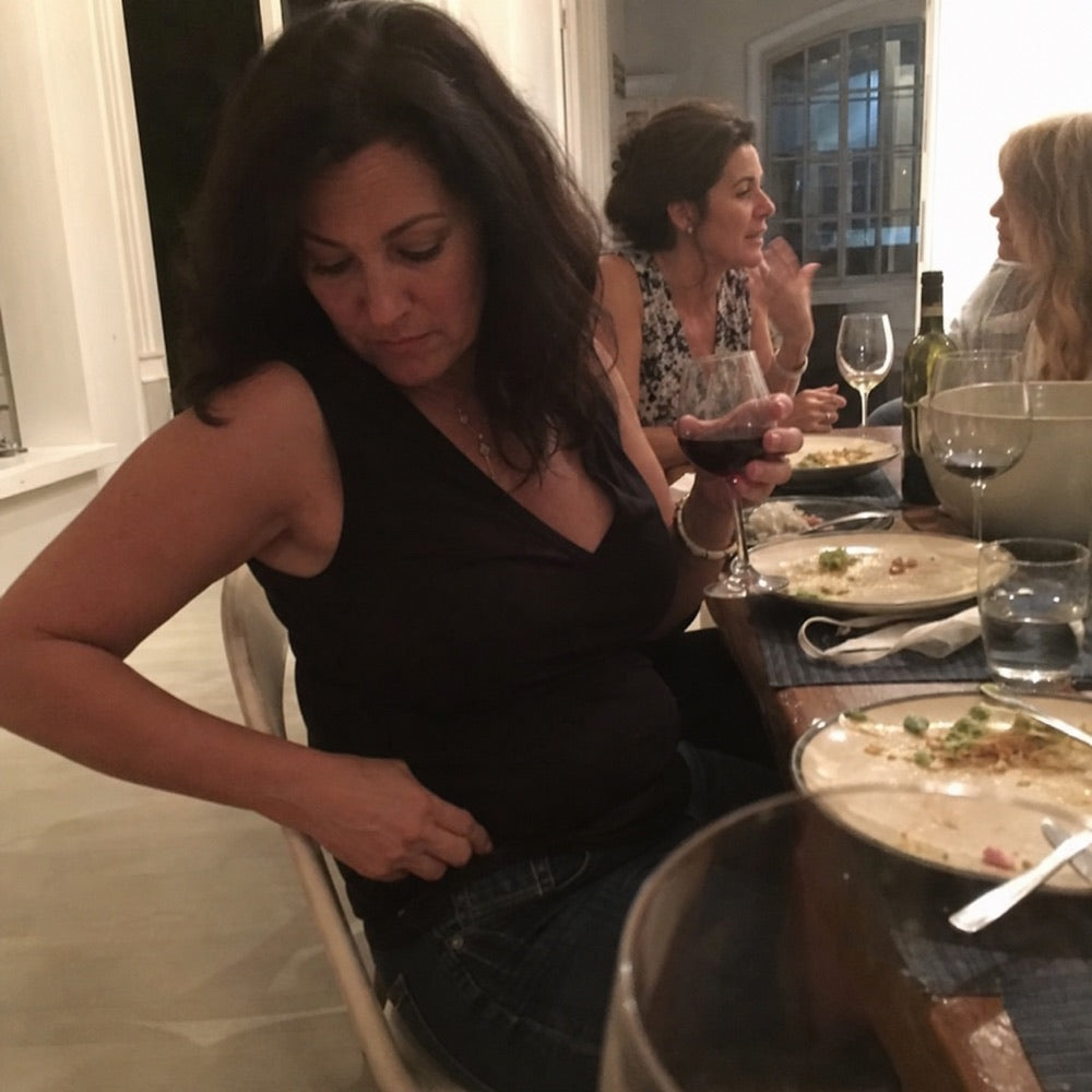 Woman discreetly adjusting her waistband during dinner with friends